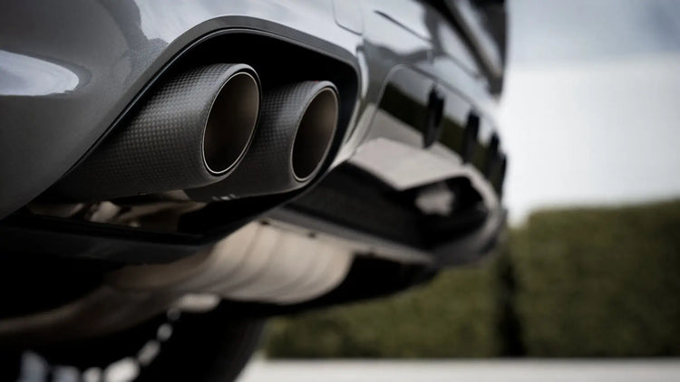 Close-up of Akrapovic carbon tailpipes on Porsche Cayenne 536.2 with Evolution Line performance exhaust, low-angle view.