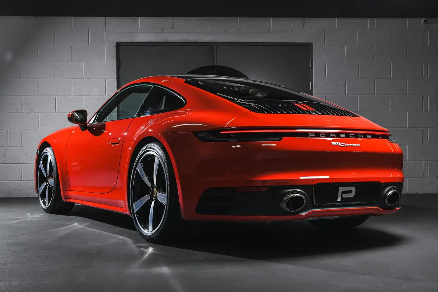 Rear angle shot of Porsche 992 Carrera in Performance Workshop post-installation, featuring Akrapovic Slip-On Race Line performance exhaust.