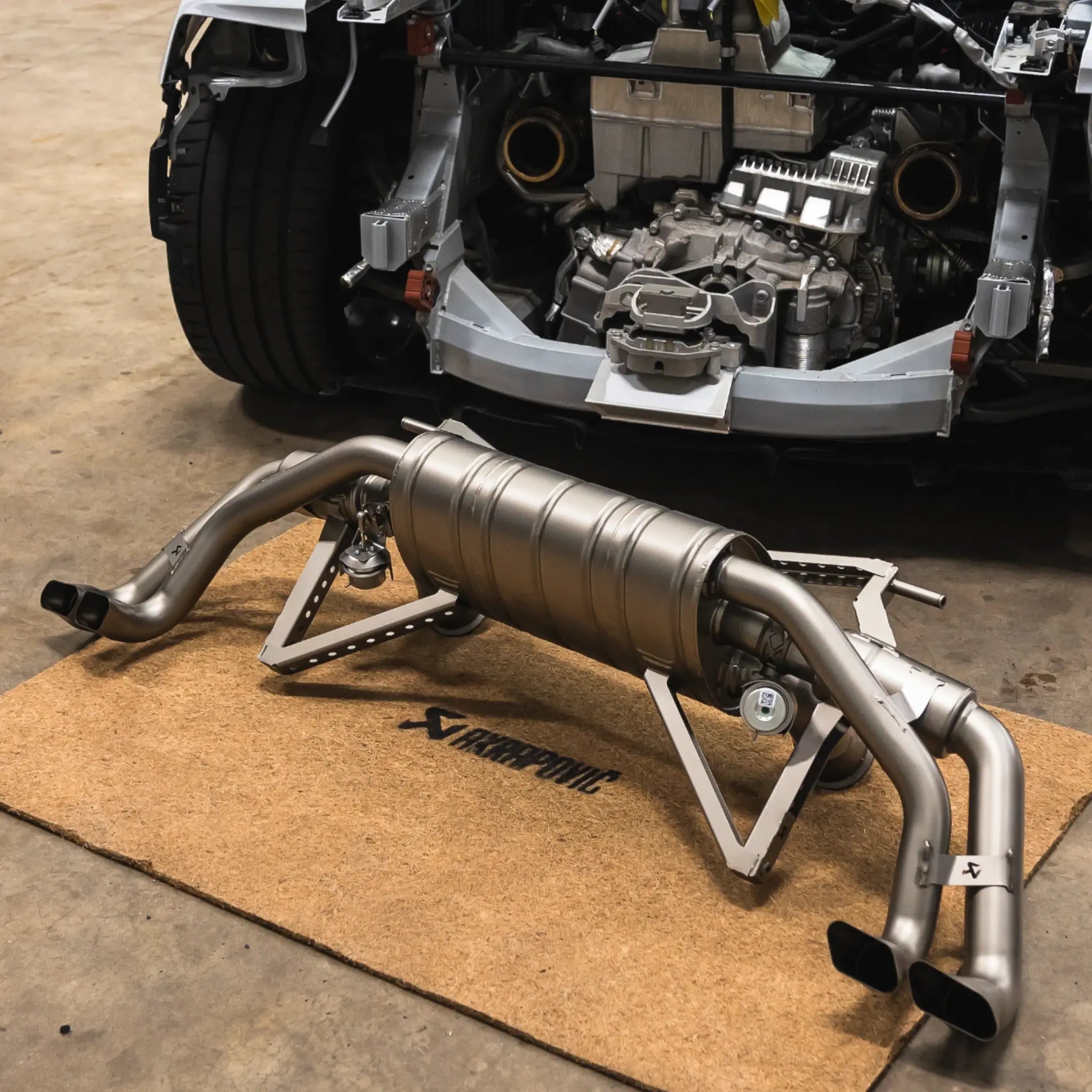 The Akrapovič Slip-On Line (Titanium) exhaust system laid out behind an Audi R8, showcasing its advanced design, titanium construction, and high-grade components.