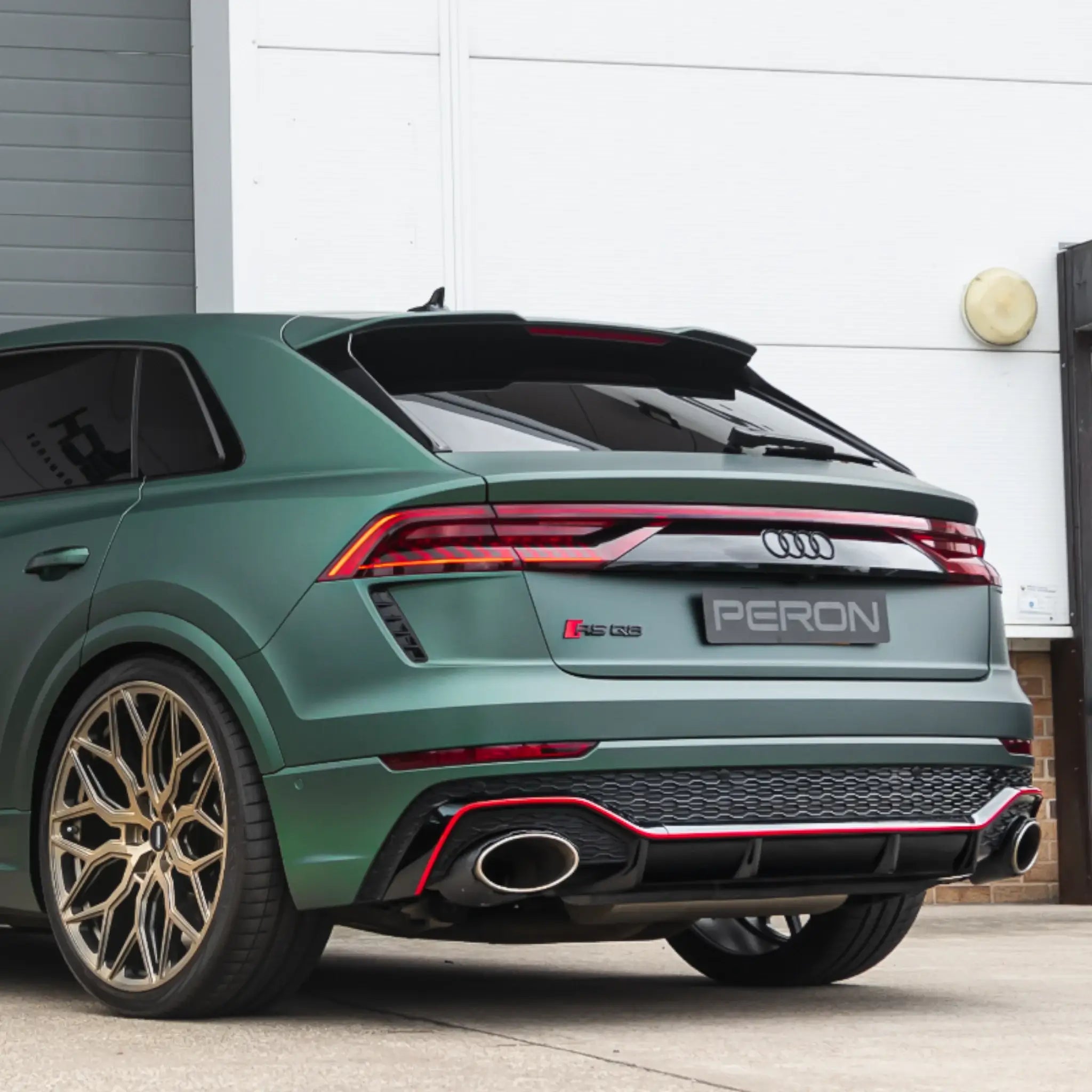 Audi RS Q8 equipped with the Akrapovič Evolution Line (Titanium) exhaust system, parked outside PERON's Performance Workshop, showcasing seamless integration and design.