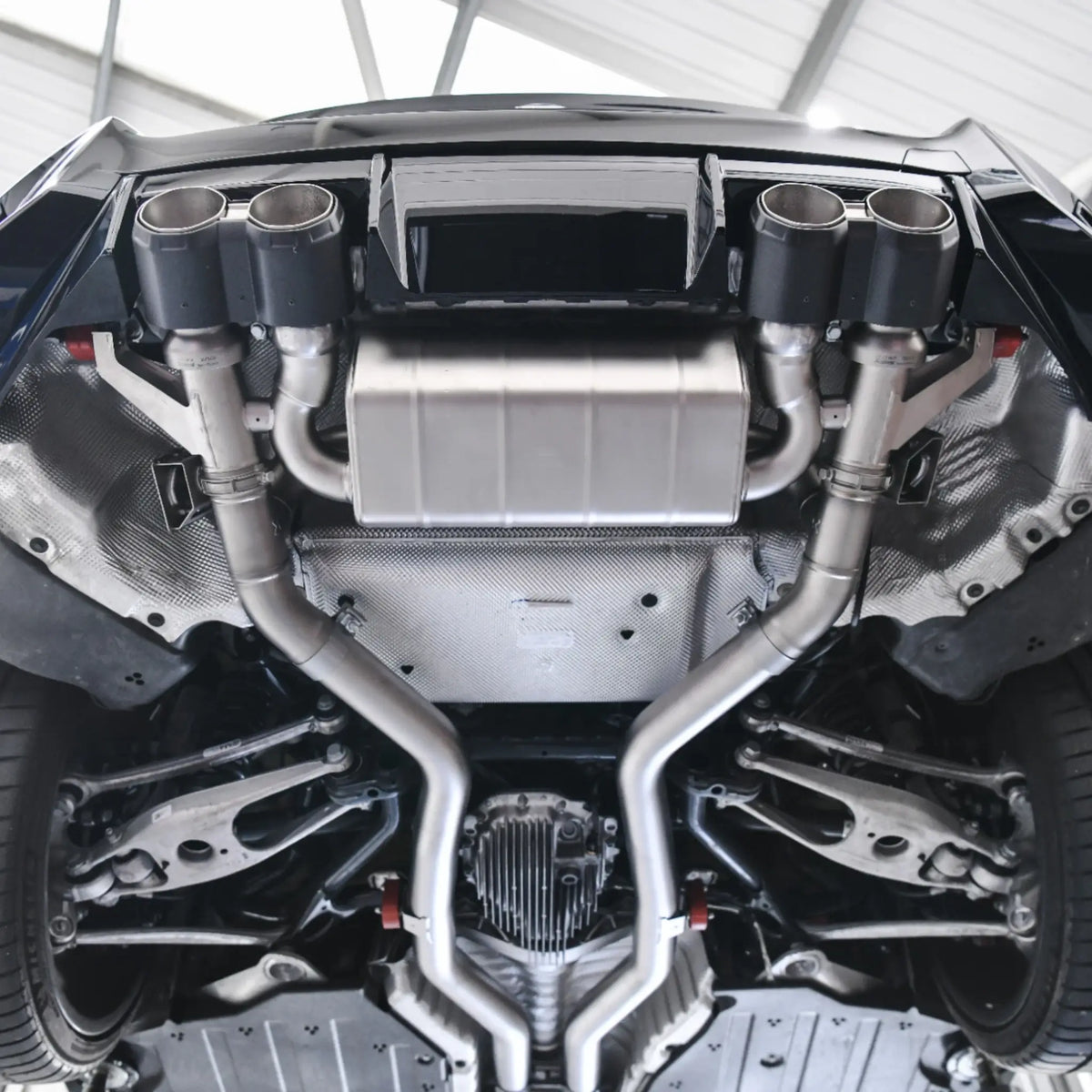 Underneath view of BMW M2 G87 with Akrapovic Slip-On Line Titanium Performance Exhaust installed, highlighting smaller back box and sleek titanium system.