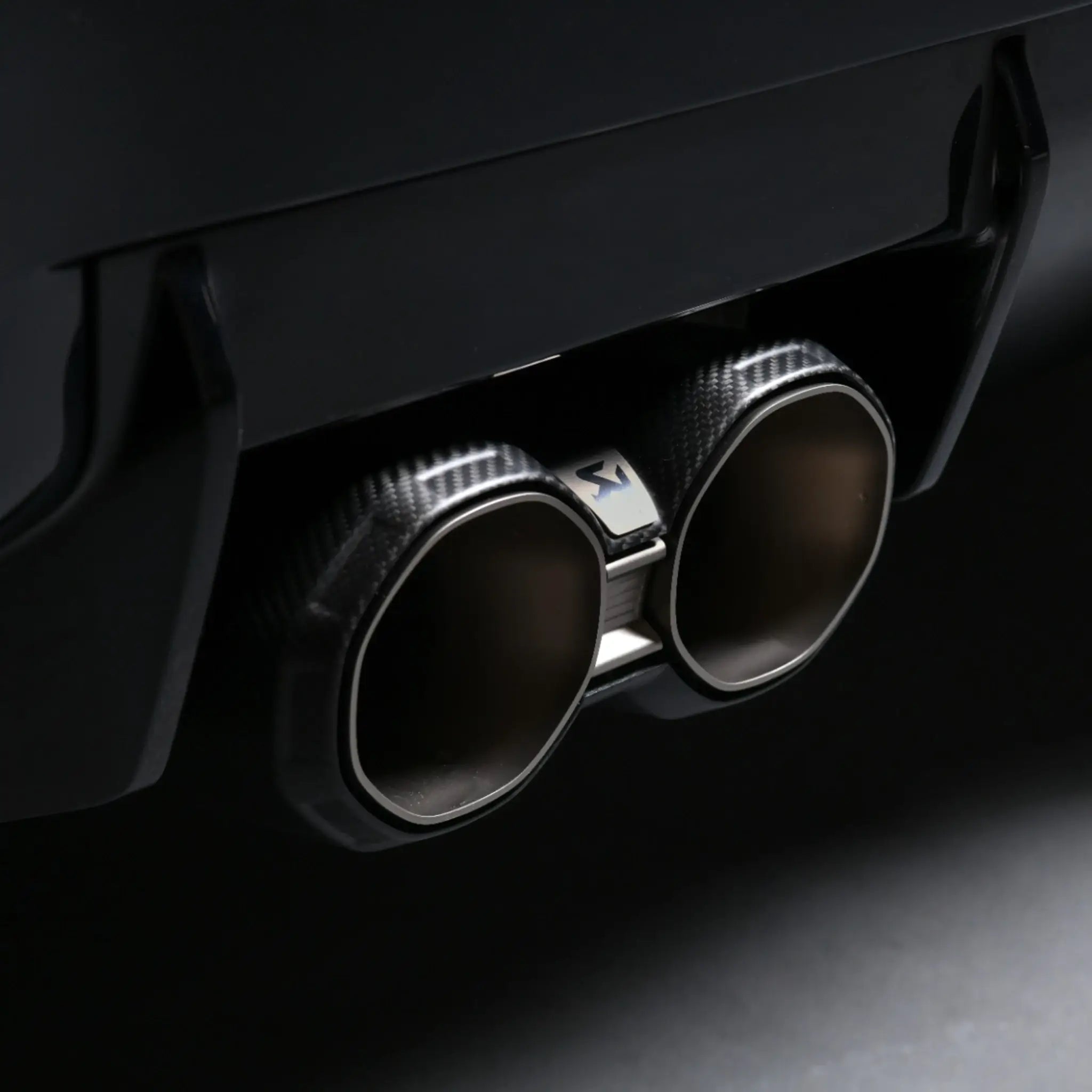 Close-up of Akrapovic octagonal titanium tailpipes installed on BMW M2 G87, captured in PERON Automotive’s Performance Workshop.