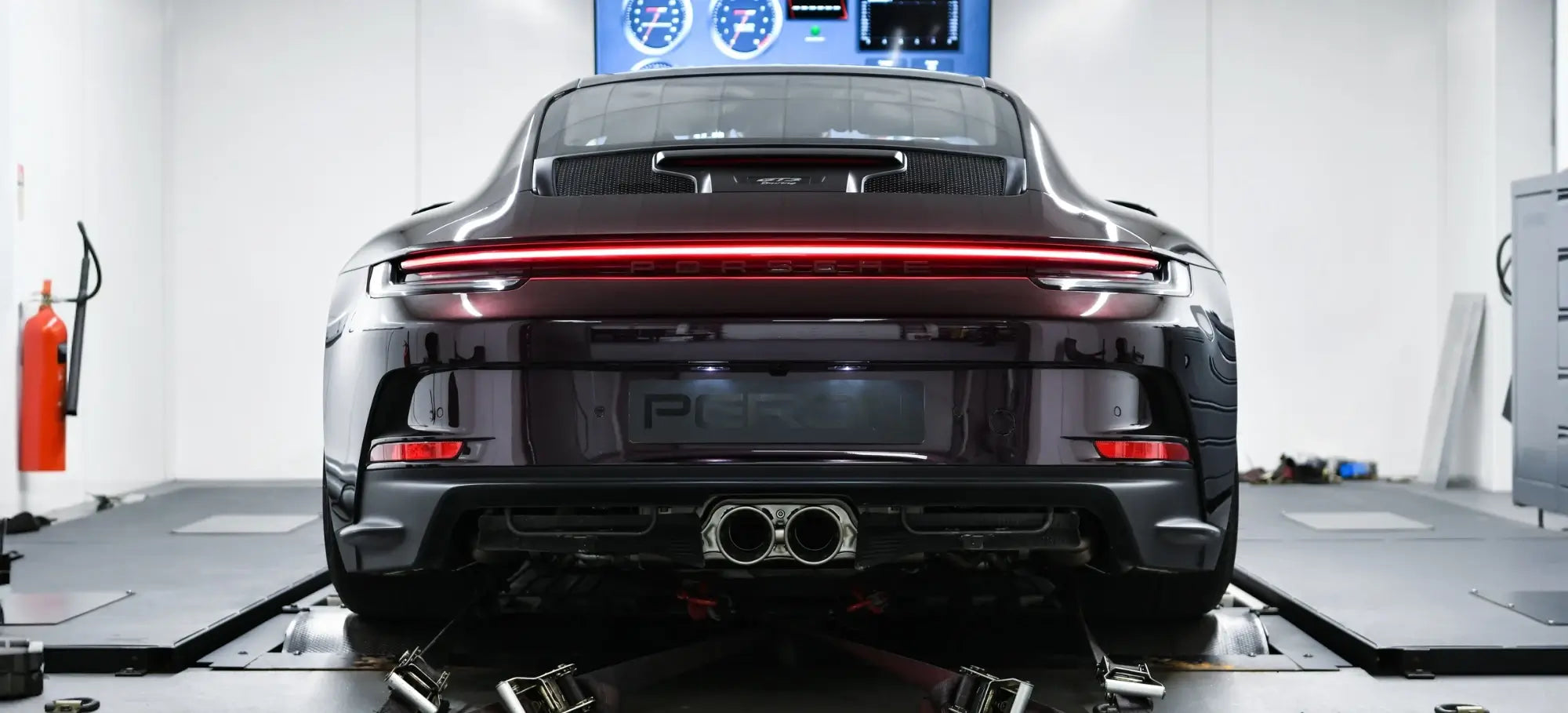 Porsche 992 GT3 Touring strapped down on the in-house Dynojet 424x Linked Dyno Cell, showcasing the Akrapovič performance exhaust as the central focus.