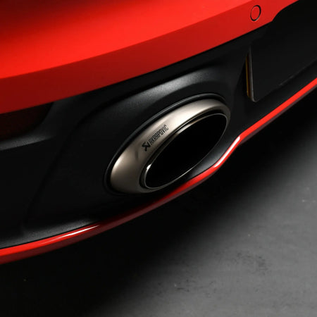 Close-up shot of Akrapovic titanium tailpipe with engraved logo on Porsche 911 Carrera 992.

