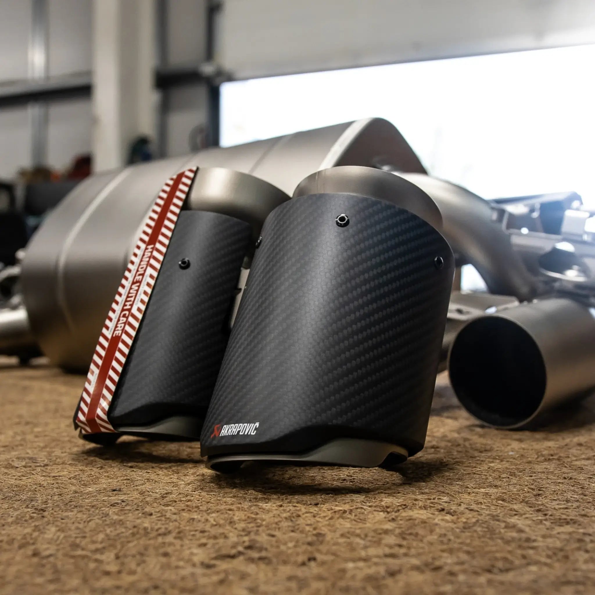 Close-up detail shot of the Akrapovic tailpipes for the F87N BMW M2, highlighting the craftsmanship and finish pre-installation.