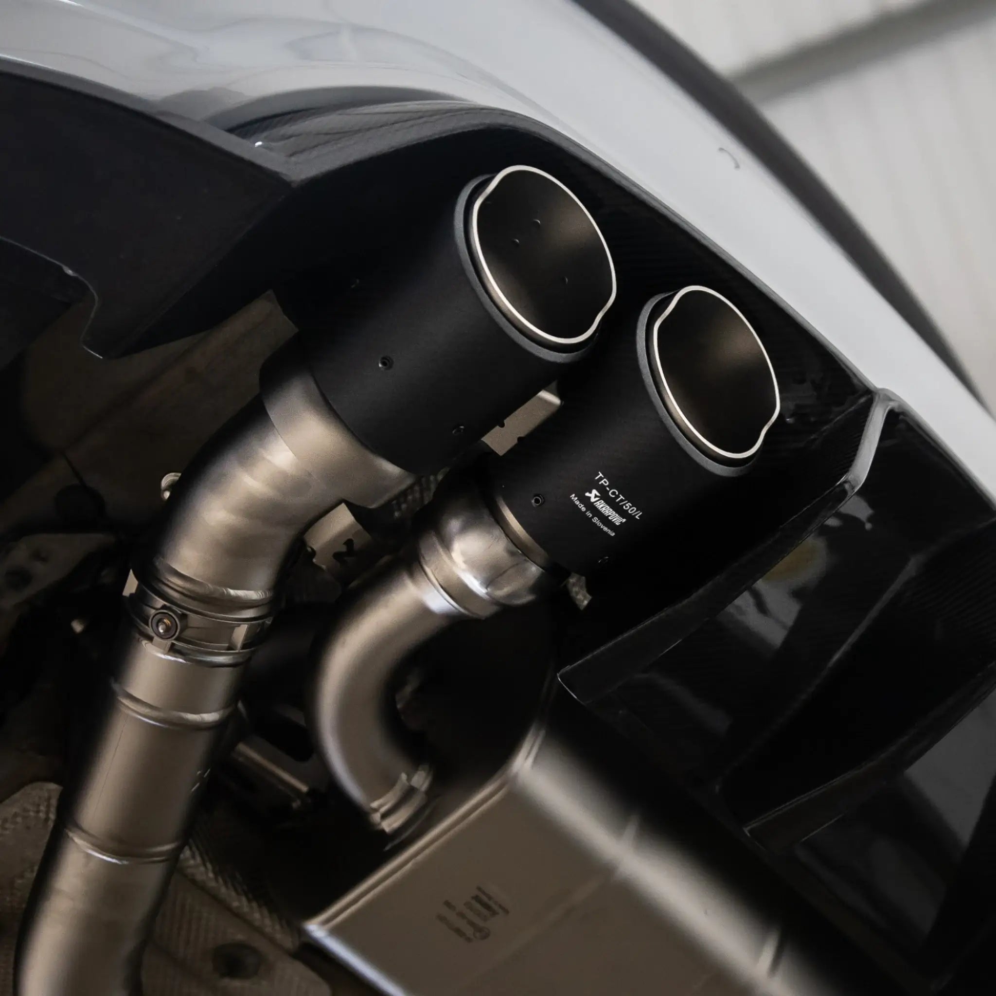 Underneath shot of the F87N BMW M2, featuring the Akrapovic exhaust system’s carbon tailpipes and lightweight titanium construction.